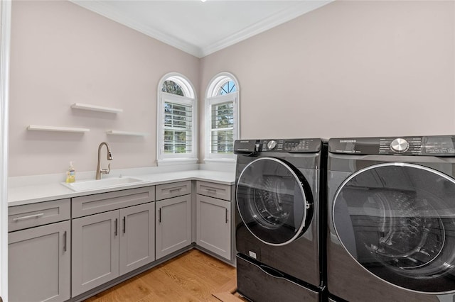 laundry area with cabinet space, washer and dryer, light wood-style floors, and a sink