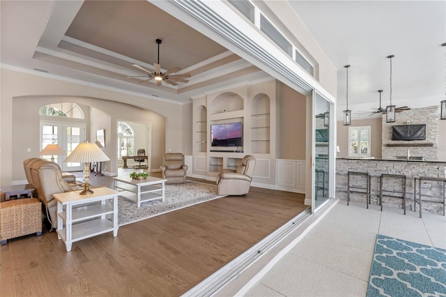 living area with a tray ceiling, ceiling fan, and wood finished floors