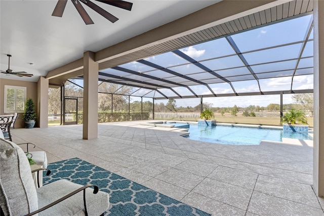 view of swimming pool featuring a ceiling fan, a pool with connected hot tub, glass enclosure, and a patio