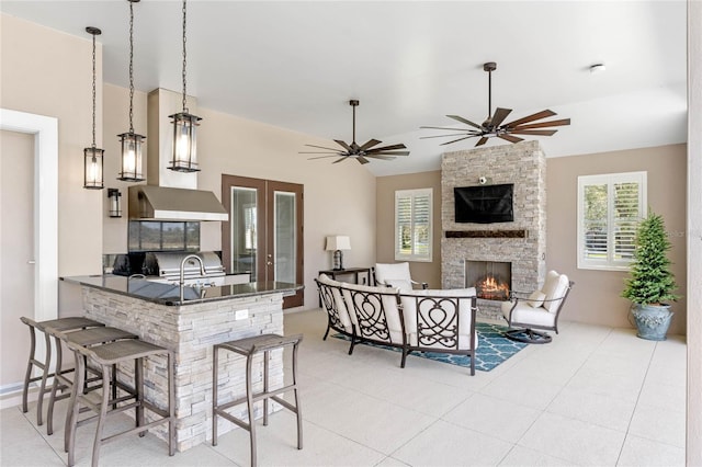 kitchen with ceiling fan, an outdoor stone fireplace, dark countertops, and a kitchen breakfast bar