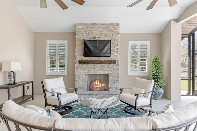 living room with vaulted ceiling, a stone fireplace, and ceiling fan