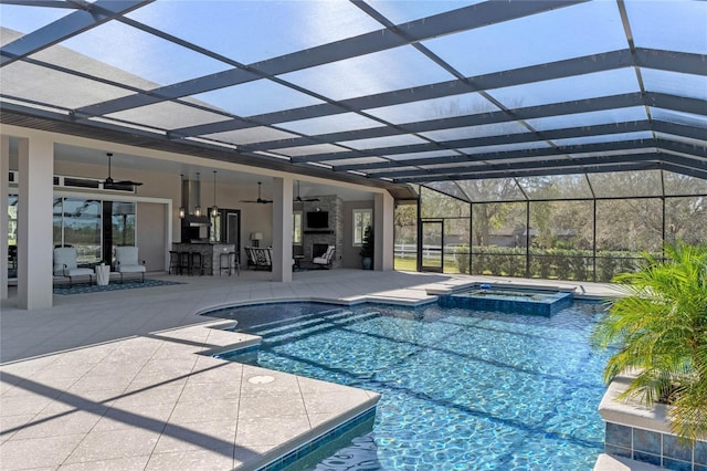 view of pool featuring a patio, outdoor dry bar, a pool with connected hot tub, a ceiling fan, and glass enclosure