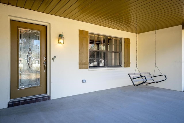 doorway to property with a porch and stucco siding