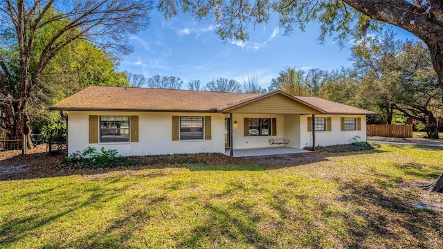 single story home with stucco siding, fence, a front lawn, and a patio