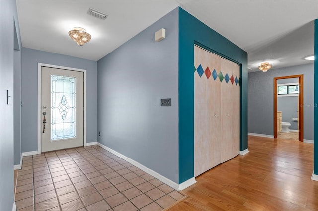 entrance foyer with a wealth of natural light, baseboards, visible vents, and light wood finished floors