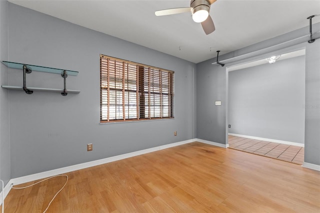 unfurnished room with wood finished floors, a ceiling fan, and baseboards