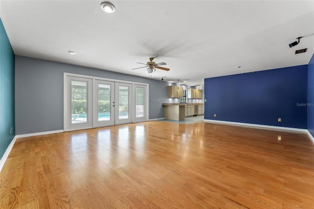 unfurnished living room with baseboards, a ceiling fan, visible vents, and light wood-style floors