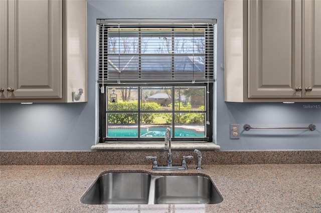 kitchen featuring light stone counters and a sink