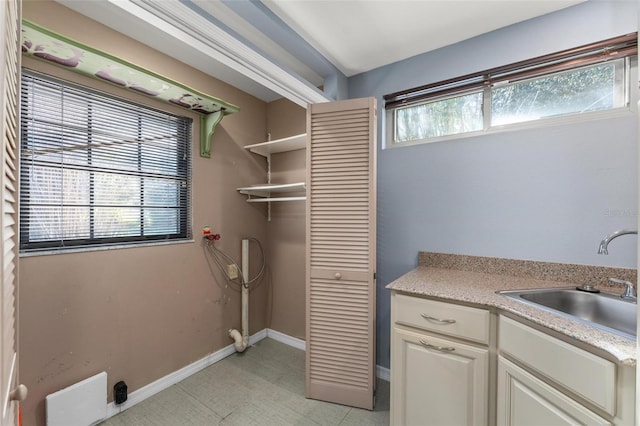 clothes washing area with laundry area, a sink, and baseboards