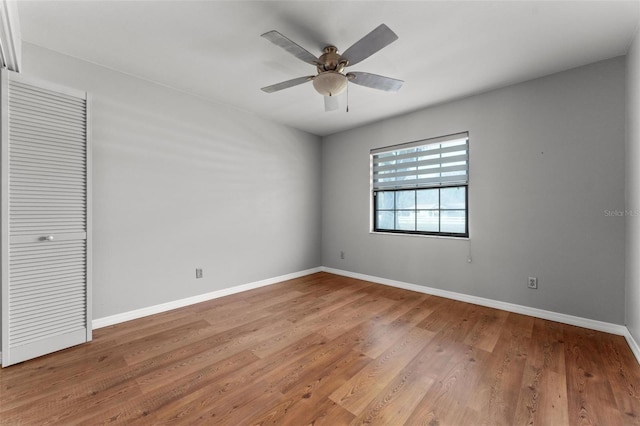 empty room with a ceiling fan, baseboards, and wood finished floors