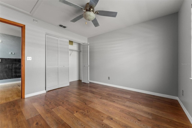 unfurnished bedroom with wood finished floors, a ceiling fan, visible vents, baseboards, and a closet