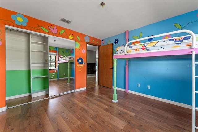 unfurnished bedroom featuring a closet, visible vents, baseboards, and wood finished floors