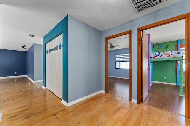 hall with visible vents, baseboards, and wood finished floors