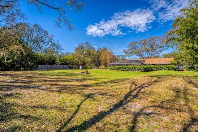 view of yard featuring glass enclosure and fence