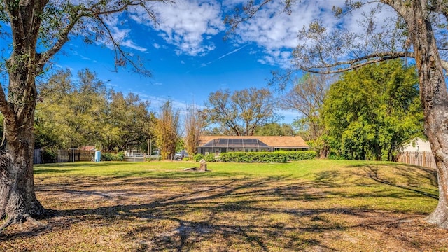 view of yard featuring glass enclosure and fence