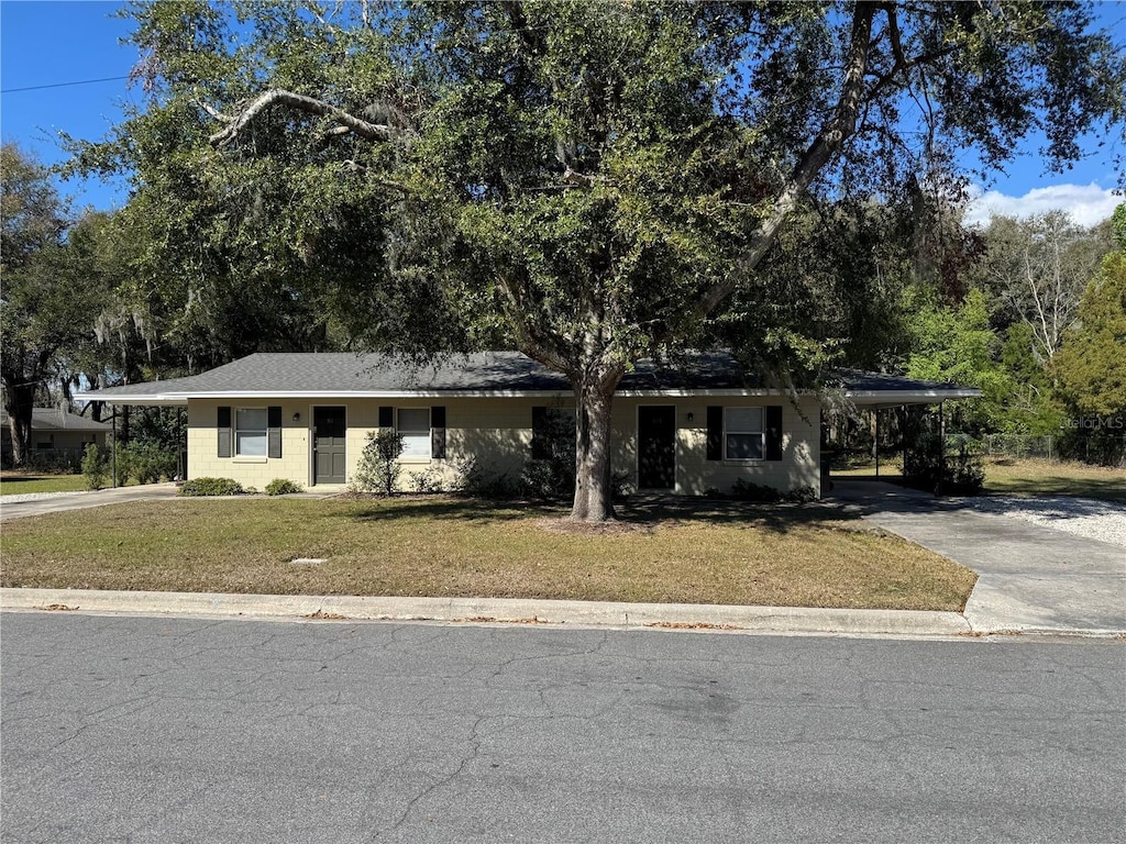 view of front facade featuring a carport, concrete driveway, and a front lawn