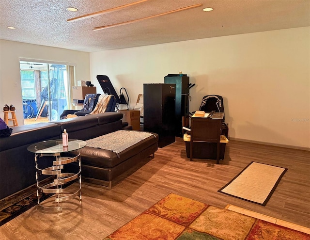 living area with a textured ceiling, recessed lighting, wood finished floors, and baseboards