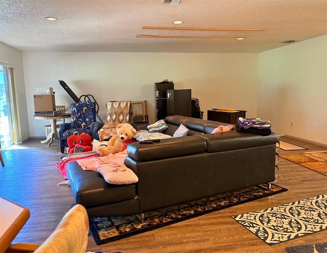 living room with a textured ceiling, baseboards, and wood finished floors