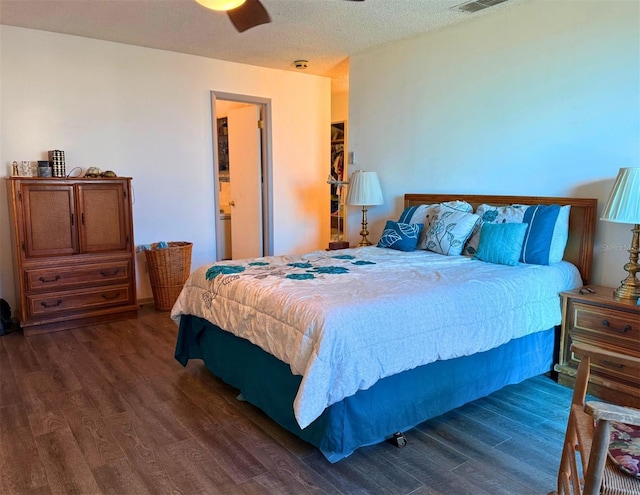 bedroom featuring a ceiling fan, dark wood-style flooring, visible vents, and a textured ceiling