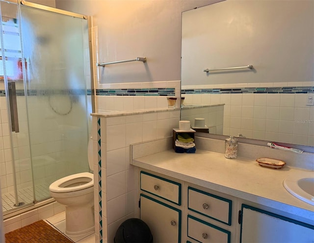 bathroom with toilet, tile patterned floors, vanity, a shower stall, and tile walls