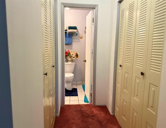 corridor featuring baseboards, carpet, and tile patterned floors