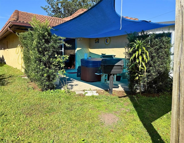 rear view of property with a yard, a tile roof, a patio area, and stucco siding