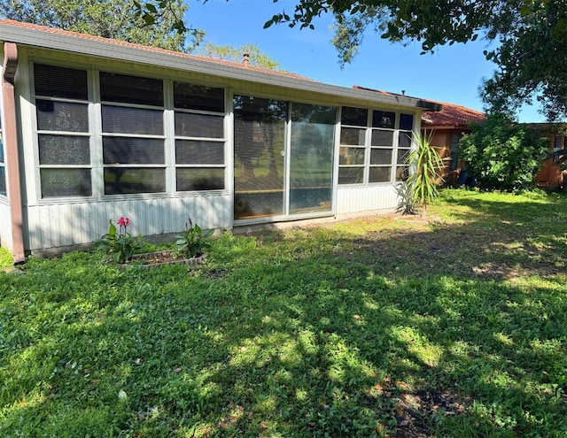 back of property with a sunroom and a lawn