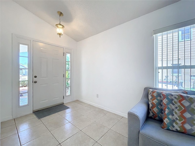 foyer with light tile patterned floors, baseboards, plenty of natural light, and vaulted ceiling