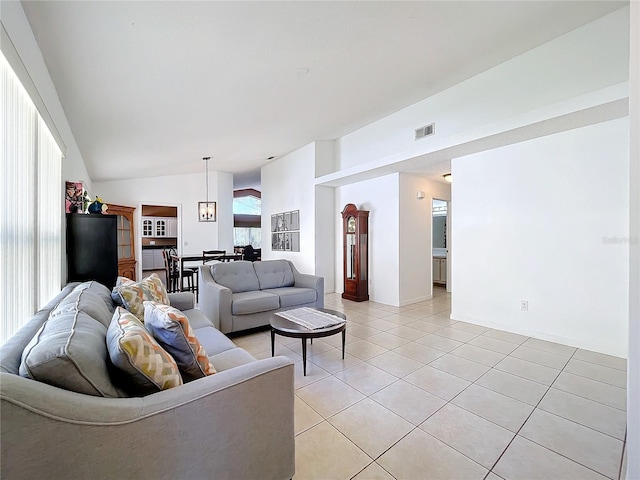 living room featuring light tile patterned floors, visible vents, and lofted ceiling