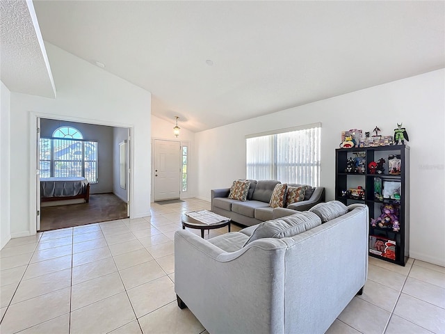 living area with light tile patterned floors, baseboards, and vaulted ceiling