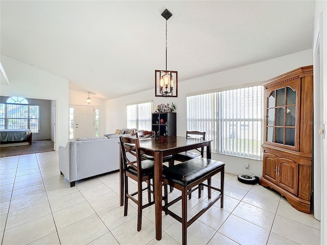 dining area featuring light tile patterned floors, an inviting chandelier, and lofted ceiling