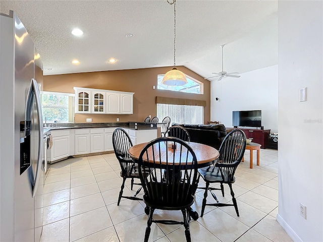 dining space featuring light tile patterned floors, a textured ceiling, ceiling fan, and vaulted ceiling