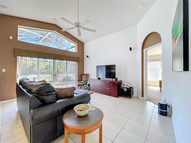 living area featuring high vaulted ceiling, light tile patterned flooring, a ceiling fan, and a textured ceiling