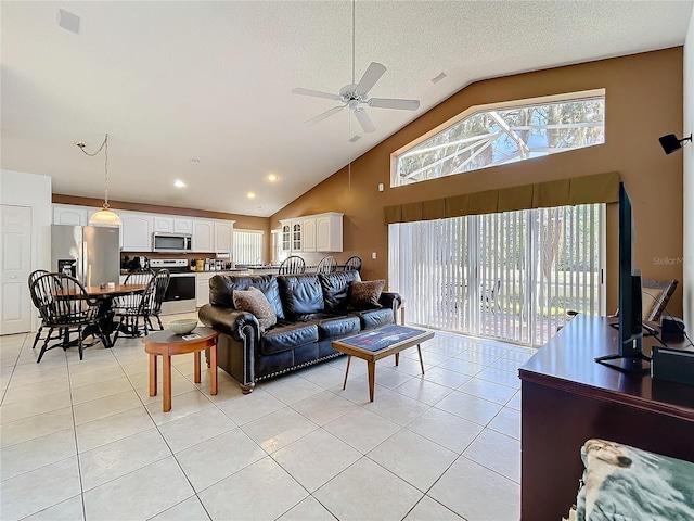 living area with light tile patterned floors, a textured ceiling, ceiling fan, and high vaulted ceiling