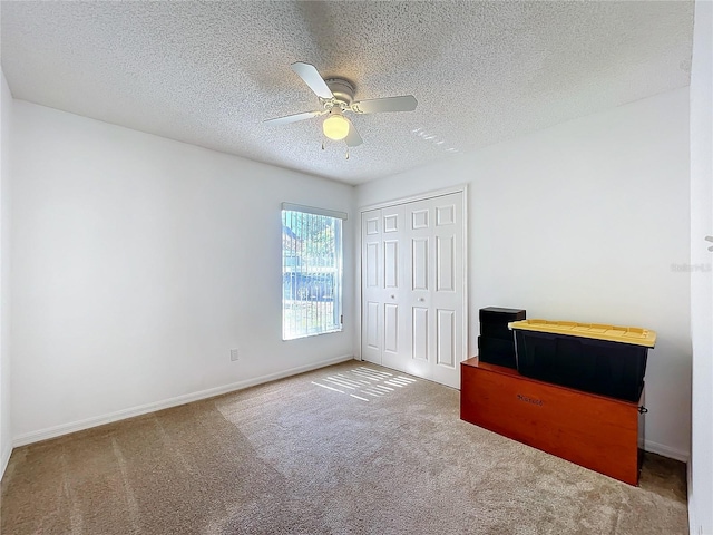 unfurnished bedroom featuring a closet, carpet flooring, a textured ceiling, and baseboards