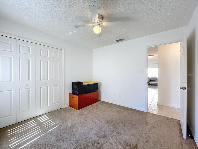 unfurnished bedroom with carpet flooring, visible vents, a closet, and a textured ceiling