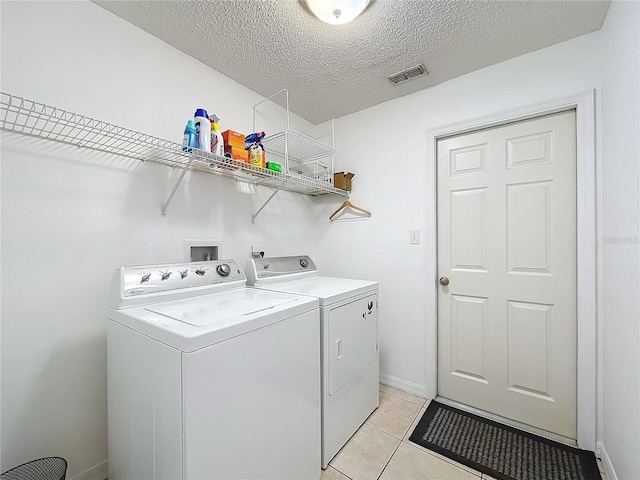 laundry room featuring visible vents, a textured ceiling, light tile patterned floors, laundry area, and washing machine and clothes dryer