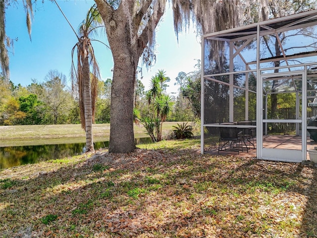 view of yard with glass enclosure and a water view