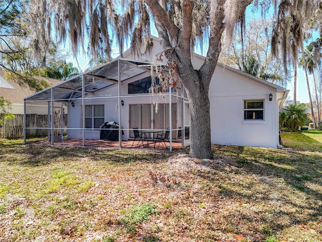 rear view of property featuring glass enclosure, a yard, a patio area, and fence