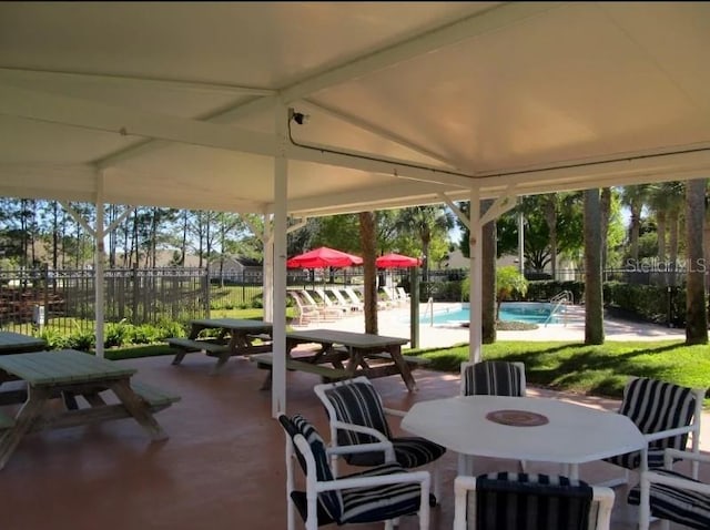 view of patio with outdoor dining area, a community pool, and fence