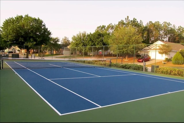 view of tennis court with community basketball court and fence