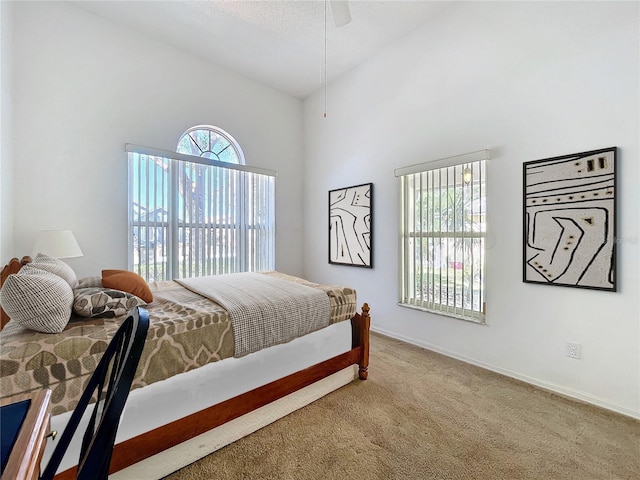 bedroom with high vaulted ceiling, baseboards, and carpet