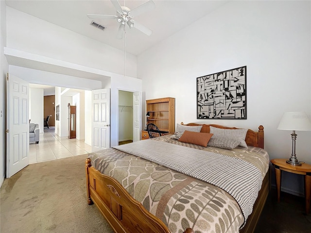 bedroom with light tile patterned floors, visible vents, high vaulted ceiling, a closet, and light carpet