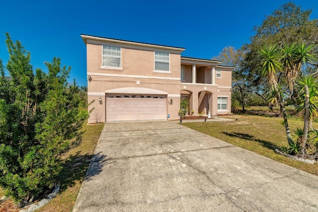 traditional-style house with a garage, concrete driveway, a front lawn, and stucco siding