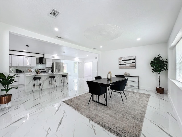 dining area featuring marble finish floor, visible vents, a textured ceiling, and baseboards