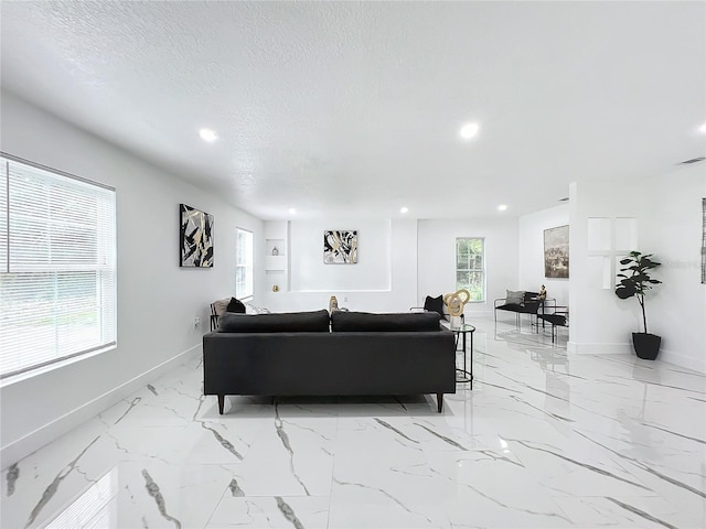 living area featuring recessed lighting, marble finish floor, a textured ceiling, and baseboards