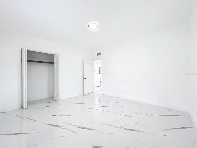 unfurnished bedroom featuring marble finish floor, a closet, visible vents, and baseboards