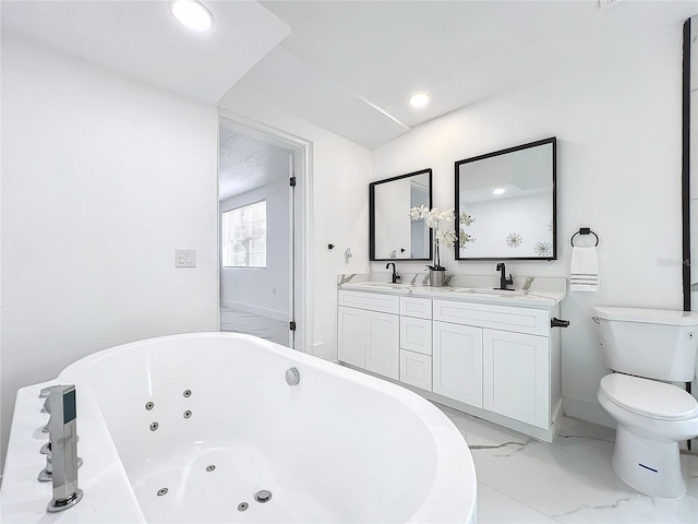 bathroom featuring marble finish floor, double vanity, toilet, a sink, and a tub with jets