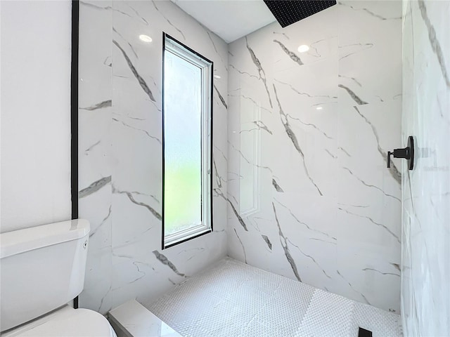 bathroom featuring a marble finish shower and toilet