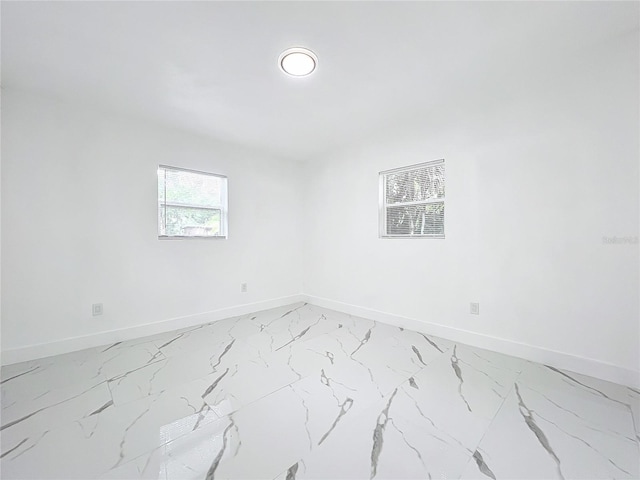 unfurnished room featuring marble finish floor and baseboards